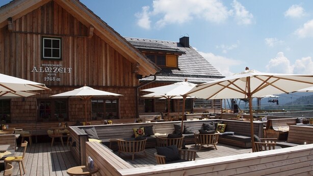 A wooden building with outdoor seating and umbrellas, featuring a sign that reads "Hochschober Almzeit Hütte 1968". - Chalet Royal with in-house wellness and large living room, large new balcony #23 (Turrach)