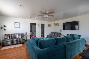 Relax in this stylish living room with a large sectional sofa, flat-screen TV, and ceiling fan.