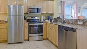 A modern kitchen with stainless steel appliances, wooden cabinets, and a granite countertop.