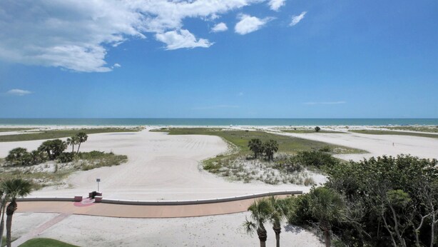 A wide, open beach with a curved viewing area and palm trees. - Surf Beach 506 - Spectacular Sunsets - Beach Front (Treasure Island)