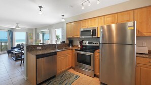 A modern kitchen with wooden cabinets, stainless steel appliances, and a view to the outside. - Surf Beach 506 - Spectacular Sunsets - Beach Front (Treasure Island)