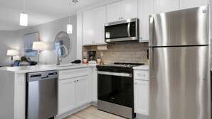 Una cocina moderna con muebles blancos, electrodomésticos de acero inoxidable, lavavajillas y cafetera.