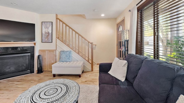 A living room with a fireplace, a sofa, a coffee table, and a staircase. - Near Beaches Town & Shopping (Naples)
