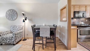 A compact living space with a dining area, a sofa, a clock, and a kitchenette. - Near Beaches Town & Shopping (Naples)