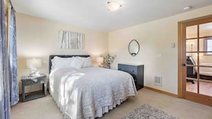 A bedroom with a bed, bedside tables, a dresser, a mirror, and a door with a view. - Near Beaches Town & Shopping (Naples)