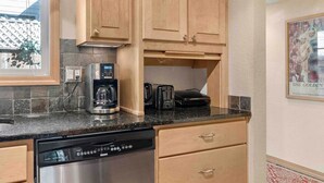 A kitchen with wooden cabinets, a coffee maker, a toaster, and a dishwasher. - Near Beaches Town & Shopping (Naples)