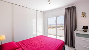 Une chambre d’hôtel avec un lit, une table de chevet, une lampe, une fenêtre avec des rideaux et une vue sur la ville.
