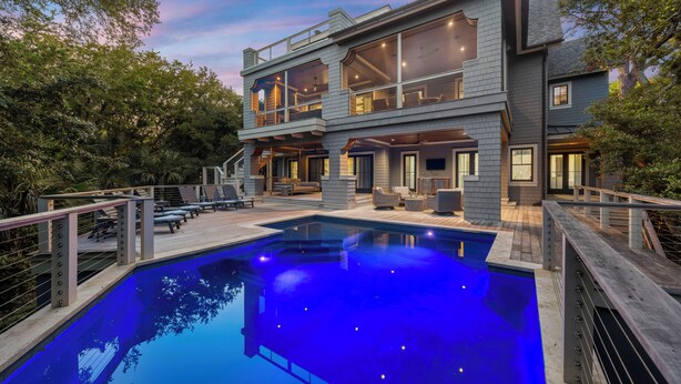 Una casa moderna de dos pisos con piscina, mobiliario exterior y terraza.