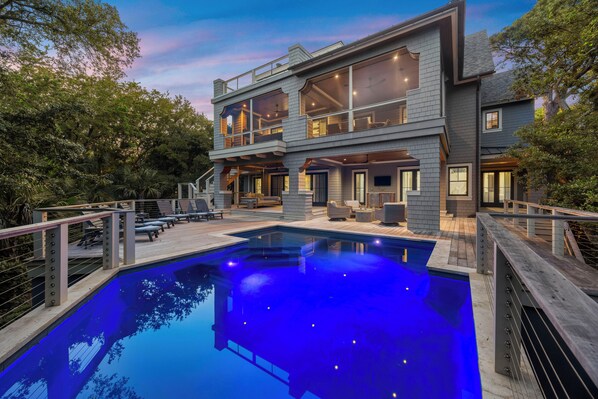 Una casa moderna de dos pisos con piscina, mobiliario exterior y terraza.