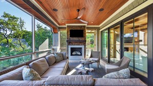 Un amplio espacio al aire libre con chimenea, asientos cómodos y ventanas grandes.