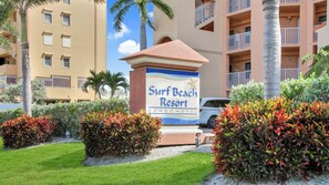 A sign for Surf Beach Resort, a condo hotel with a view of the surrounding buildings and palm trees.