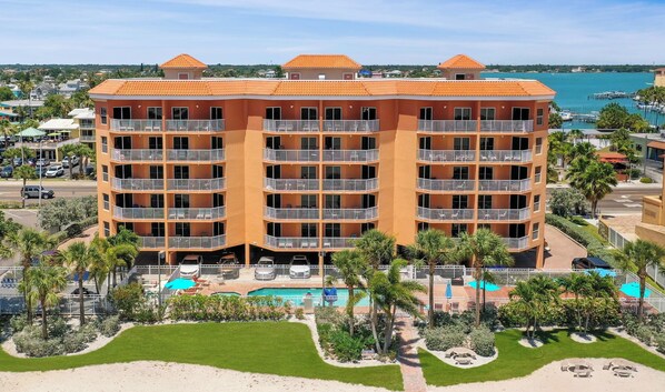 A multi-story hotel with balconies, a swimming pool, and a view of the sea.