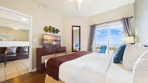 A hotel room with a bed, a TV, a dresser, a mirror, and a balcony with chairs.