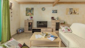 Un accogliente soggiorno con divano, tavolino, televisione e opere d'arte alle pareti.