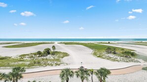 Eine Küstenlandschaft mit einem Sandstrand, Palmen und blauem Himmel.