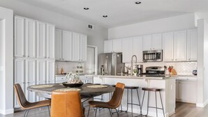 A modern kitchen with white cabinets, stainless steel appliances, and a central island with stools. - Relax in Paradise - 4 Bed + 2 Bath w/ Gorgeous Heated Private Pool & Spa! (Peoria)
