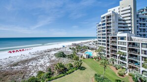Ein Strandhotel mit mehreren Balkonen, einem Pool und Blick auf den Strand.