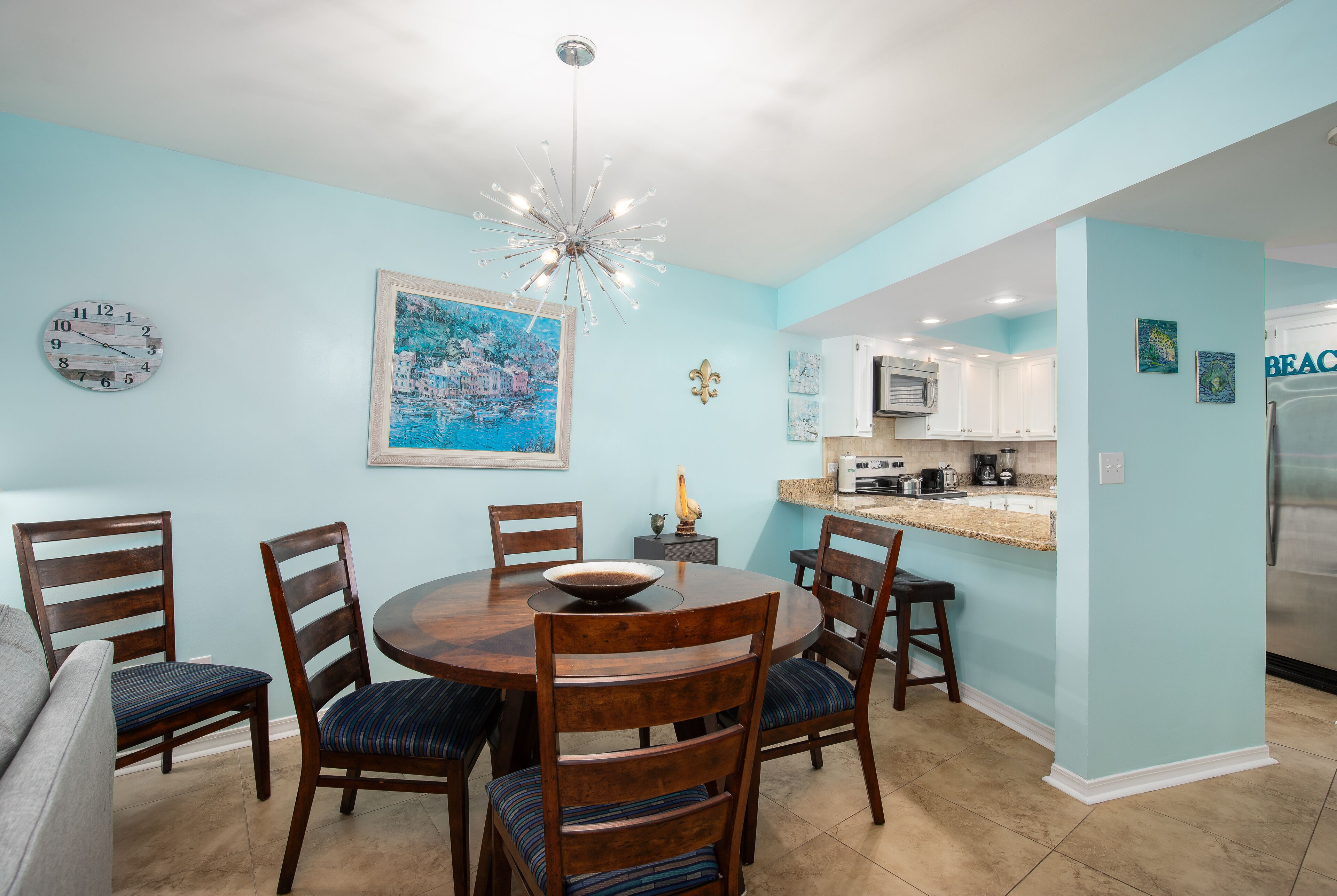 A dining area with a round wooden table, six chairs, and a chandelier.