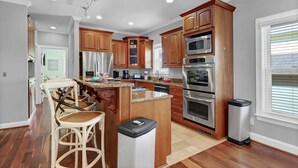 Una cocina moderna con armarios de madera, electrodomésticos de acero inoxidable y una zona de bar con sillas de mimbre.