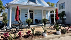 A light blue house with a porch, numbered 428, featuring outdoor seating and potted plants. - The Gregory House, A Southern Tropical Get Away! (Pensacola)