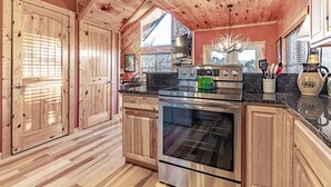 A kitchen with wooden cabinets, a stainless steel oven, and a granite countertop. - Comfort & Relaxation 3 br Cabin Wraparound Decks Amazing Views 2 Hot Tubs (Pigeon Forge)