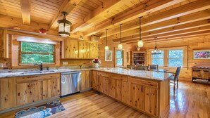 Una cocina amplia con armarios de madera, una isla central e iluminación colgante.