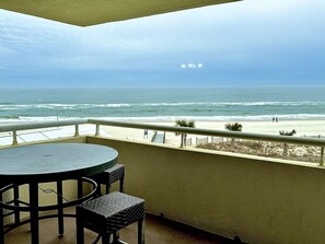 A balcony with a table and chairs, overlooking a beach with waves and a clear sky. - Directly On The Beach - Marisol del Cielo/Sea/Sun Of The Sky - Gulf Side (Pensacola)