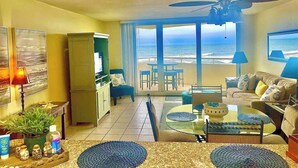 A living room with a view of the ocean, a ceiling fan, and a dining area with a table and chairs. - Marisol del Cielo/Sea Sun Of The Sky-On The Beach (Pensacola)