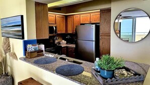 A kitchen with wooden cabinets, a stainless steel refrigerator, and a granite countertop. - Marisol del Cielo/Sea Sun Of The Sky-On The Beach (Pensacola)