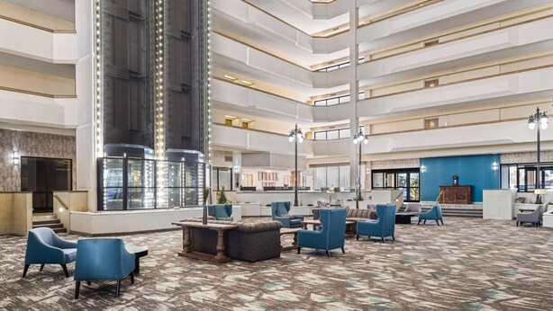 A multi-level hotel lobby with seating areas, a central column, and a reception desk.