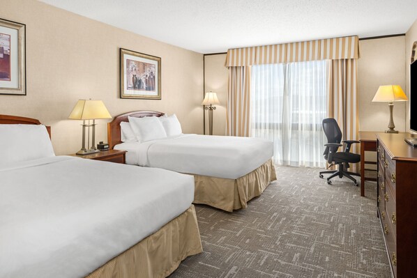 A hotel room with two beds, a desk, a chair, and a television. - Montana Trailhead Inn (Billings)