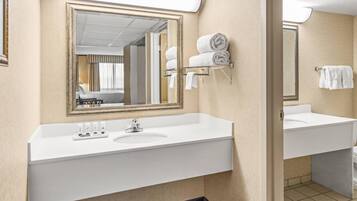 A hotel bathroom with a large mirror, two sinks, and a towel rack.