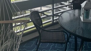 A balcony with a view of a lake, a dining table, and chairs.