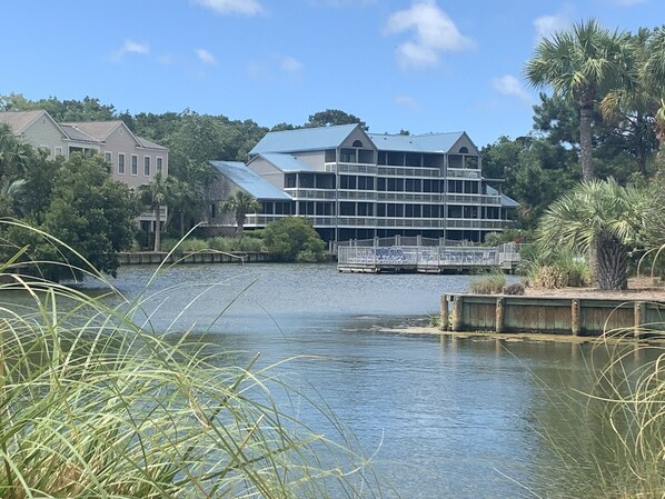 Un hôtel situé au bord de l’eau, avec un grand bâtiment doté de nombreuses fenêtres et d’une terrasse couverte.