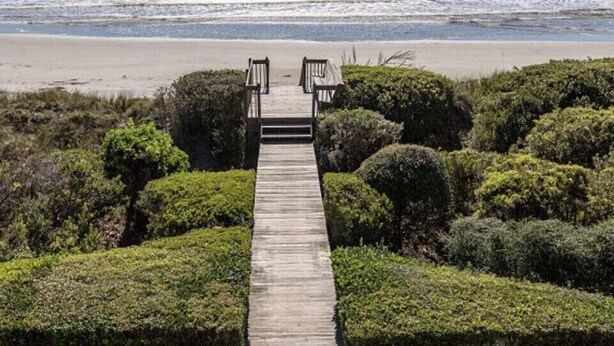 A wooden pathway leading to a beach with a view of the ocean.
