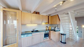 Una cocina moderna con armarios de madera, lavavajillas, horno y cafetera.