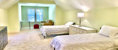 A bedroom with two beds, a desk, a chair, a dresser, and a ceiling fan.