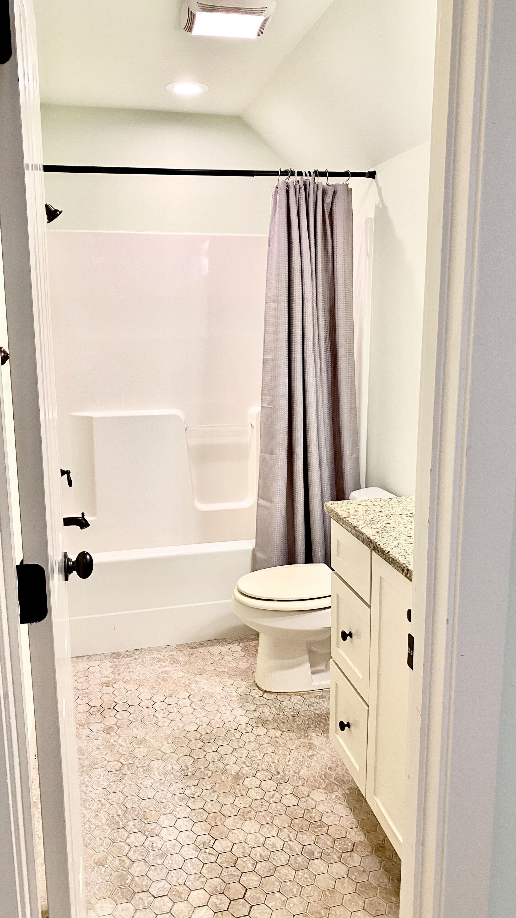 A bathroom with a shower, toilet, and vanity.
