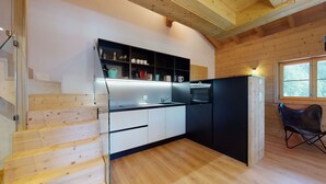A modern kitchen with wooden flooring, a built-in oven, and a black refrigerator. - Des Alpes (002) - ON THE SLOPES apartment 6 pers (Haute-Nendaz)