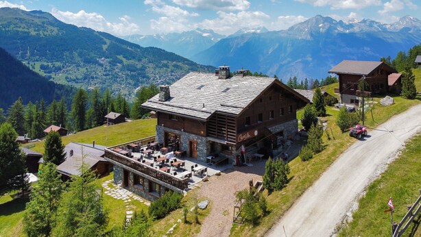 A mountain lodge with a stone facade, outdoor seating area, and a view of the surrounding mountains. - Des Alpes (002) - ON THE SLOPES apartment 6 pers (Haute-Nendaz)