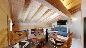 A cozy wooden dining area with a table set for two, a wine bottle, and a bowl.