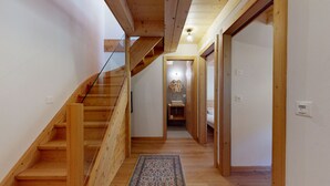 A wooden staircase leading to a bathroom with a hexagonal mirror and a sink.