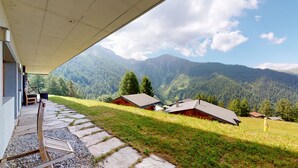 A mountain lodge with a stone pathway leading to a covered seating area.