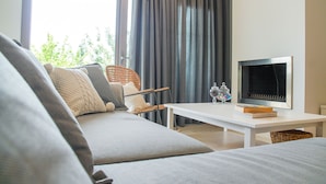 Una sala de estar moderna con un sofá, una silla de mimbre, una mesa blanca y un televisor de pantalla plana.