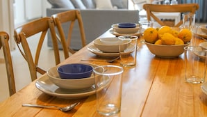 Una mesa de comedor dispuesta con fuentes, platos, vasos y un cuenco de limones.