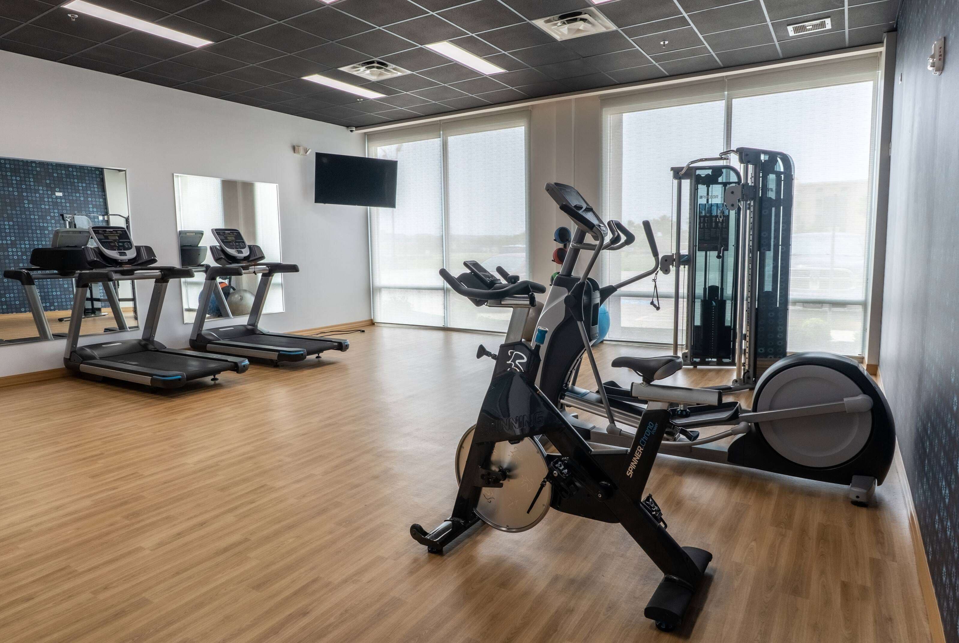 Uma academia com esteiras, elíptico e máquina de musculação.