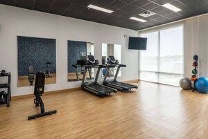 Een sportschool met loopbanden, fitnessballen en een halterbank.