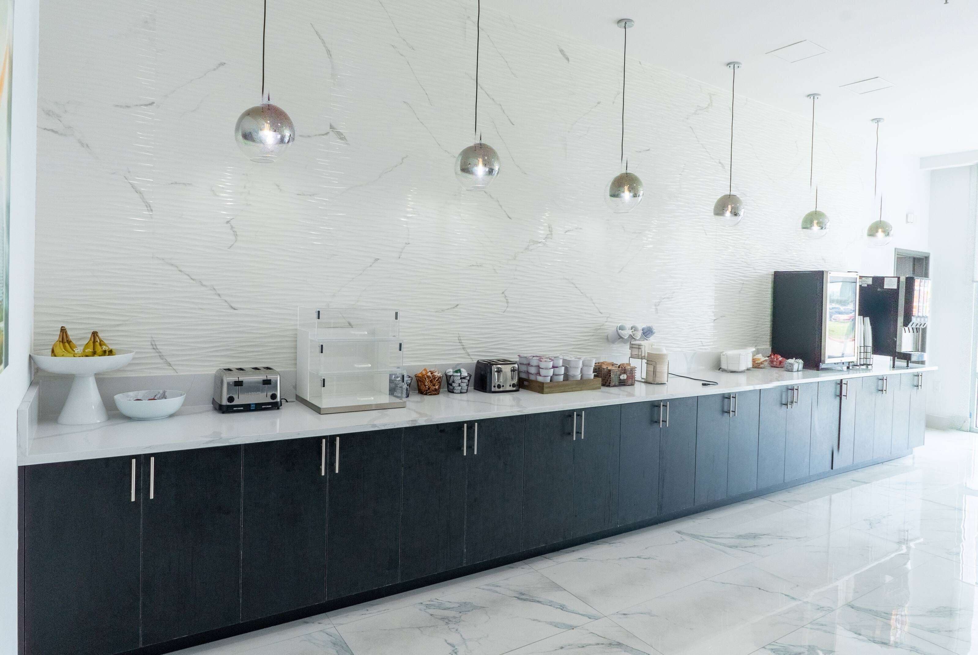Una cocina moderna con salpicadero de mármol, armarios oscuros e iluminación colgante.