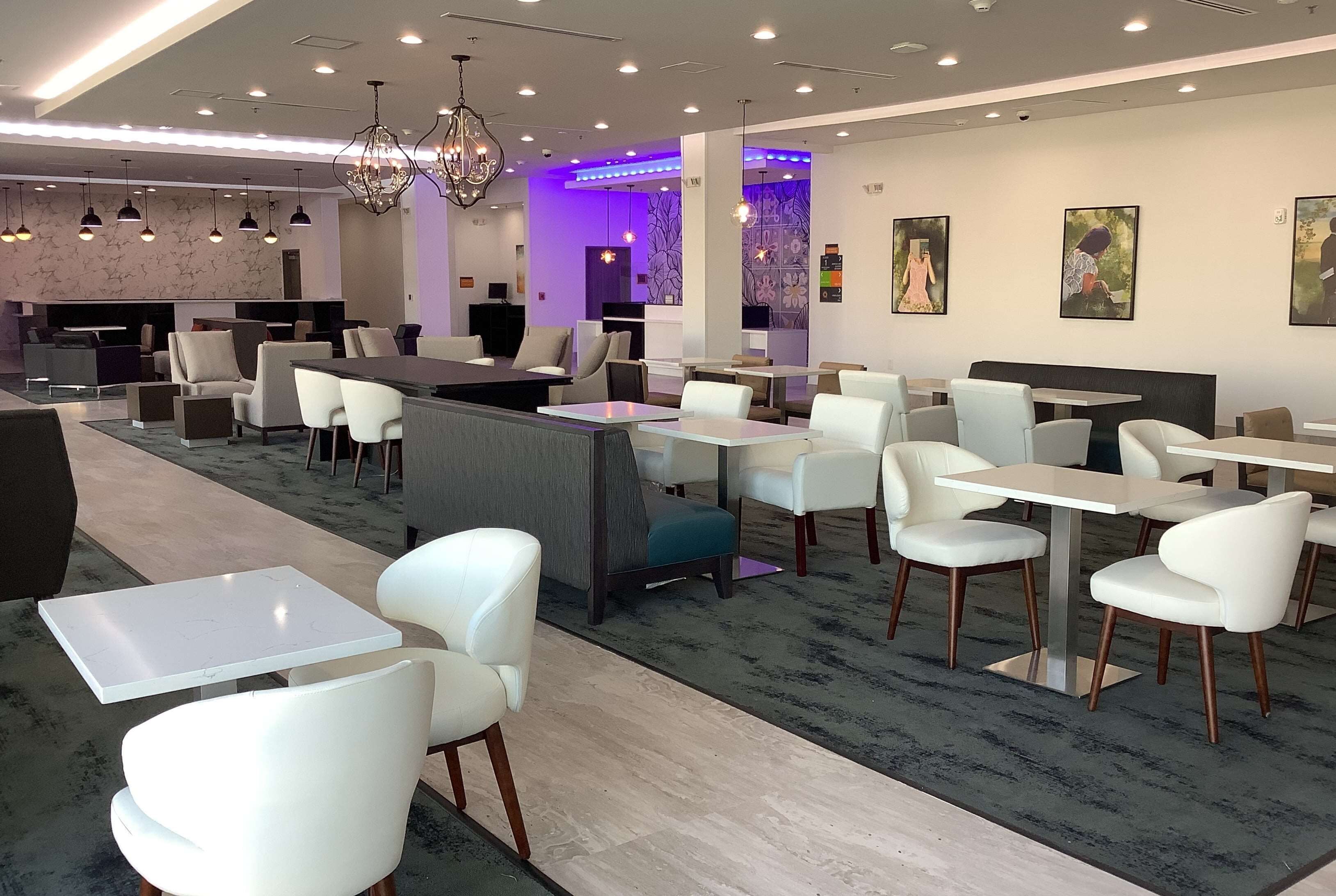 A modern restaurant with white chairs, tables, and a bar area.