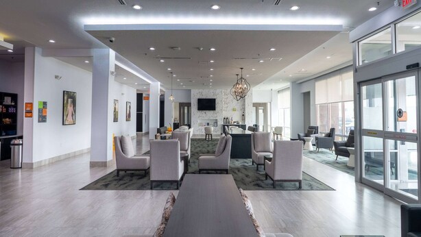 Eine moderne Lobby mit einer zentralen Sitzgruppe, einer Bar und einem an der Wand montierten Fernseher.